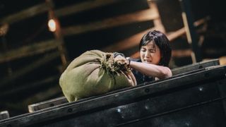 a woman hauls a sandbag into a cart, in 'physical 100' season 2