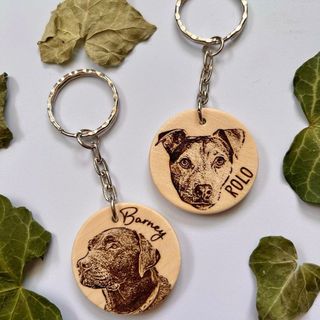 Two round wooden key rings engraved with dog faces.