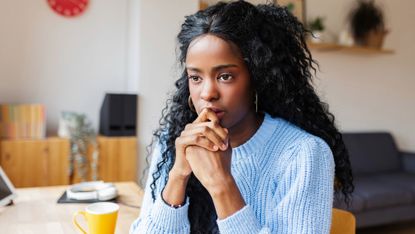Portrait of a young woman deep in thought sitting at home