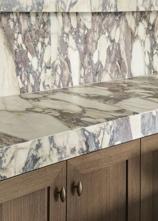 A richly veined marble has a honed edge finish, on top of wooden cabinetry