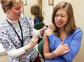Nurse Coordinator Lisa Chrisley (L) injects an experimental flu vaccine into the body of volunteer Michelle Levender (R), a medical school student, during a clinical trial to test the effectiveness of the vaccine to combat avian influenza April 5, 2005, a