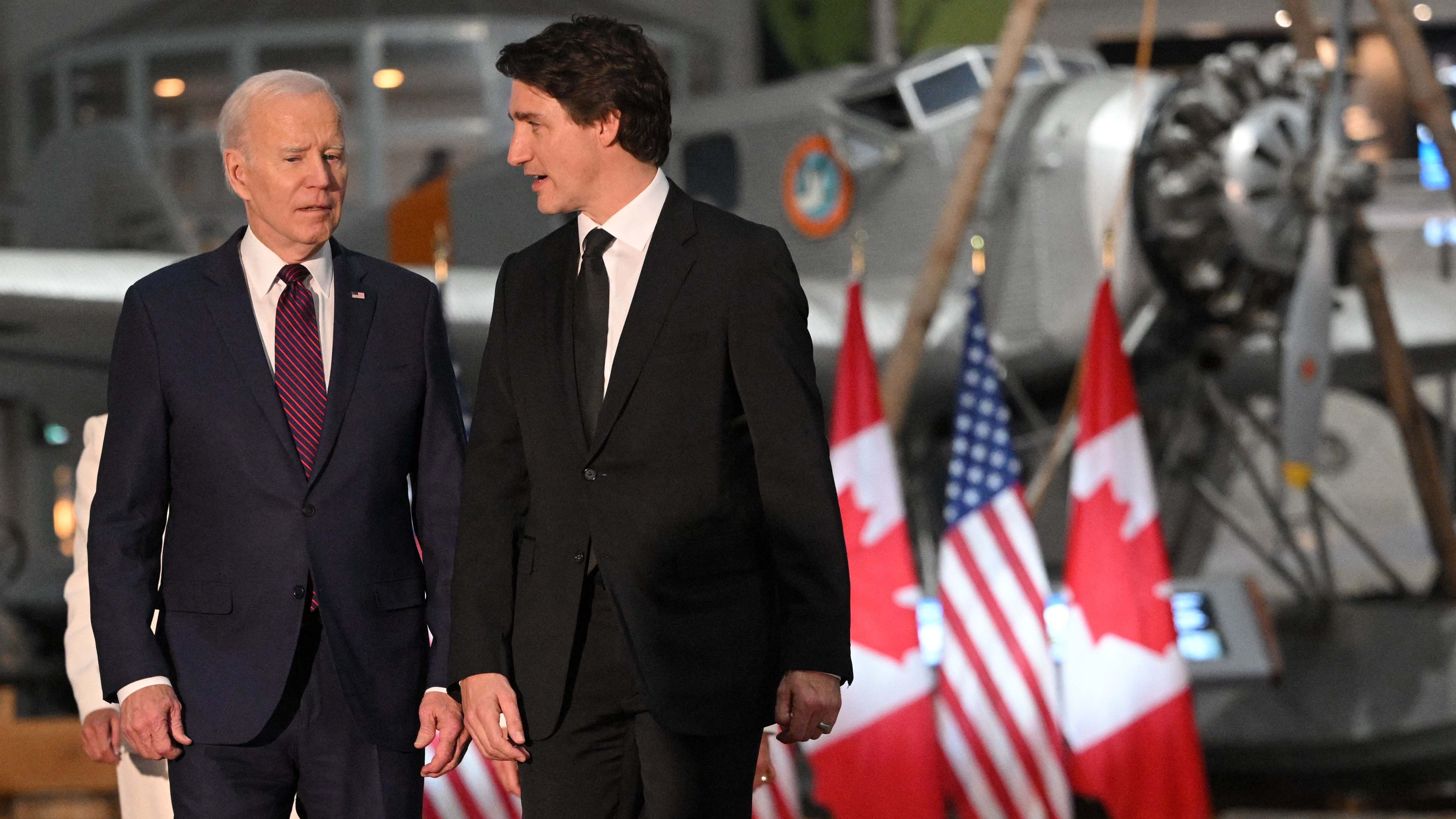 u.s. president joe biden with canadian prime minister justin trudeau walking in front of canadian and u.s. flags. behind is a junkers w34 aircraft
