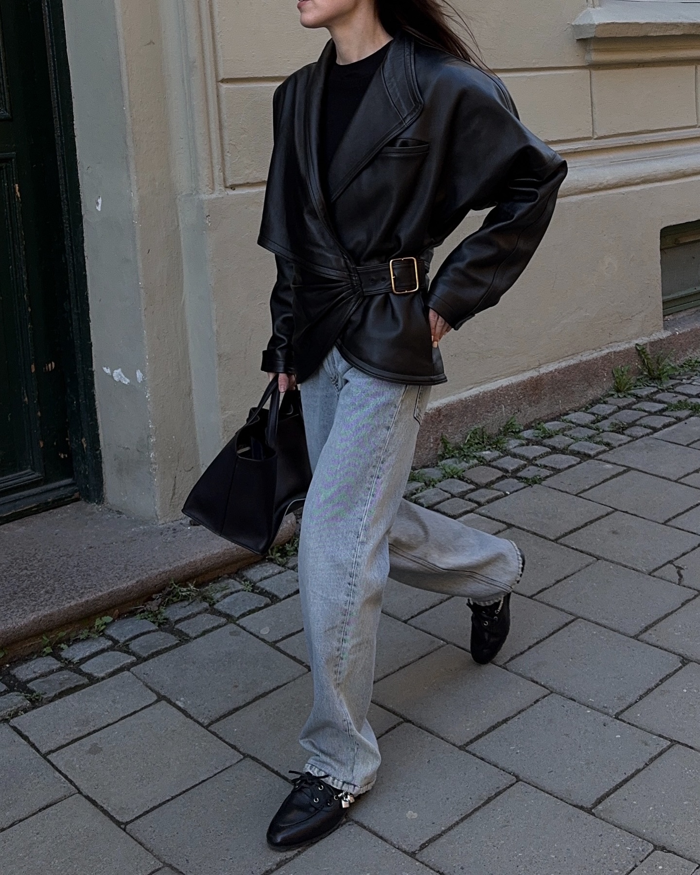 A woman wears black leather boat shoes with jeans and a black leather jacket