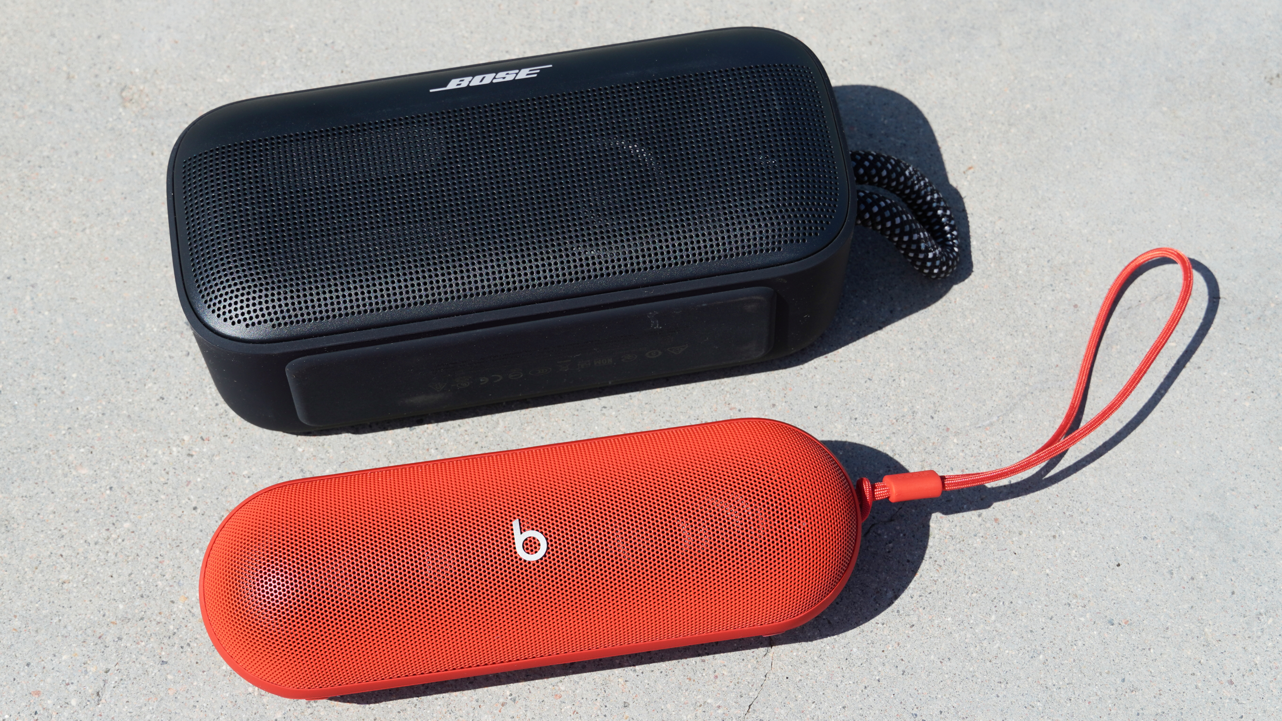 The speaker grills of the Bose SoundLink Plus (black) beside the Beats Pill (red).