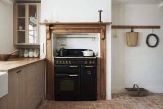 black range cooker with wooden mantlepiece and cream cabinetry