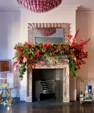 A Christmas fireplace decorated with an elaborate red floral garland