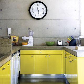 kitchen area with concrete wall and yellow kitchen cabinet