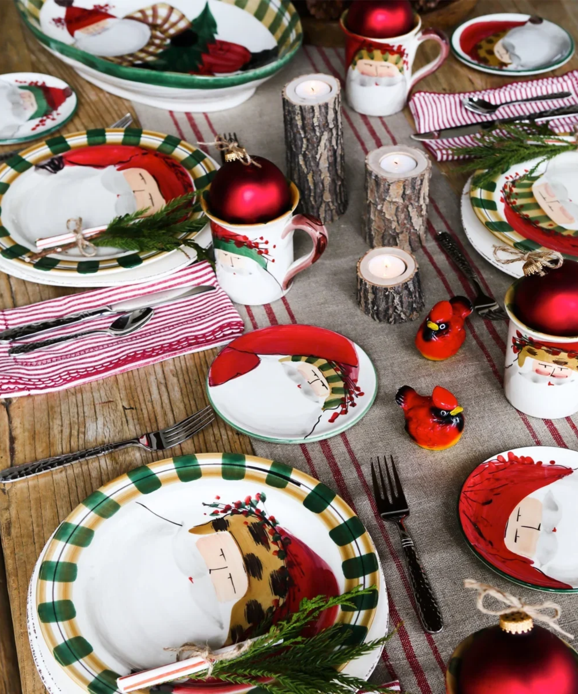 Festive Christmas tablescape featuring St. Nick-motif plates, a striped border table runner, and woodland foliage accents.