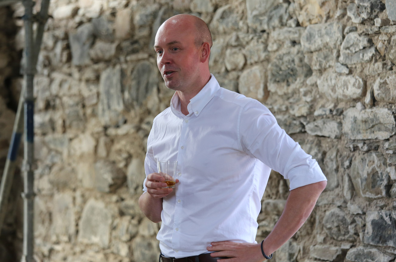 a man in a white shirt standing by a wall