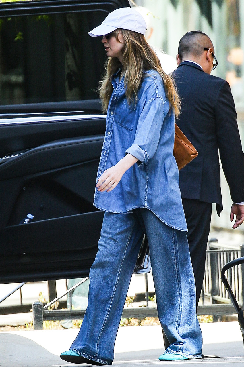 Jennifer Lawrence wearing a chambray button-down, with loose flare jeans, and teal flats and a brown suede bag