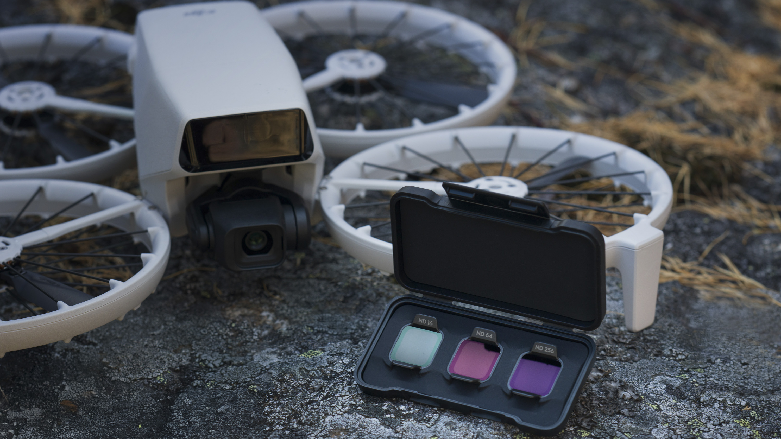 DJI Flip drone on a rock alongside ND filter case