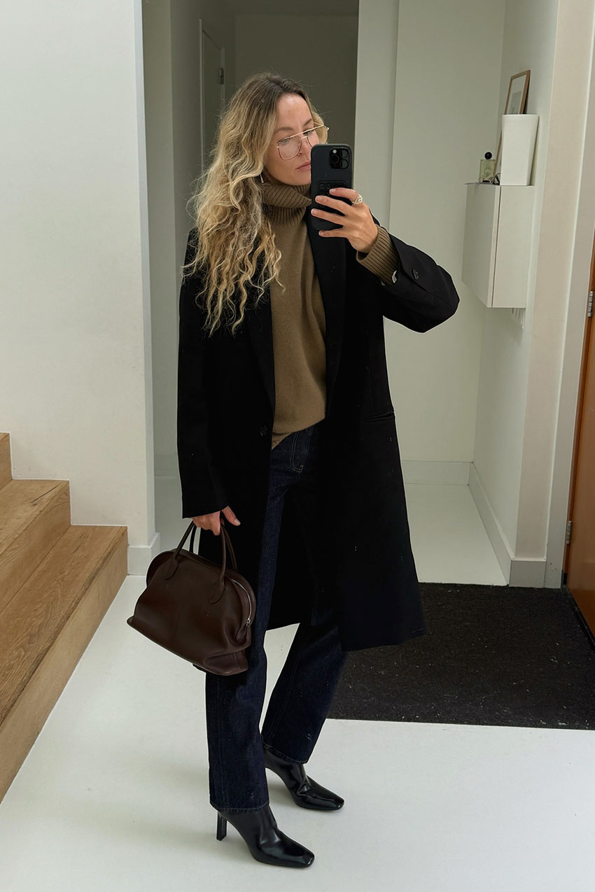 Woman wearing a black coat and brown bag.