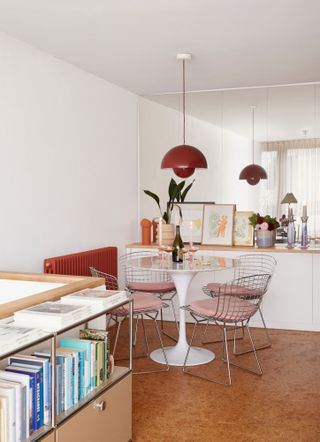 Dining area of an apartment with small glass-topped table, wire chairs and cork floor