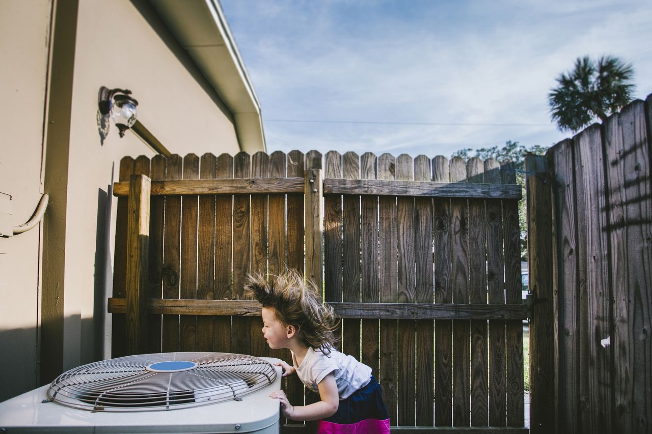 Hair of girl blowing in outdoor air conditioning unit.