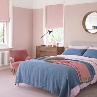 bedroom flooring ideas, pink and blue bedroom with pink carpet and walls, blue throw, pink armchair, wooden mirror, chest of drawers