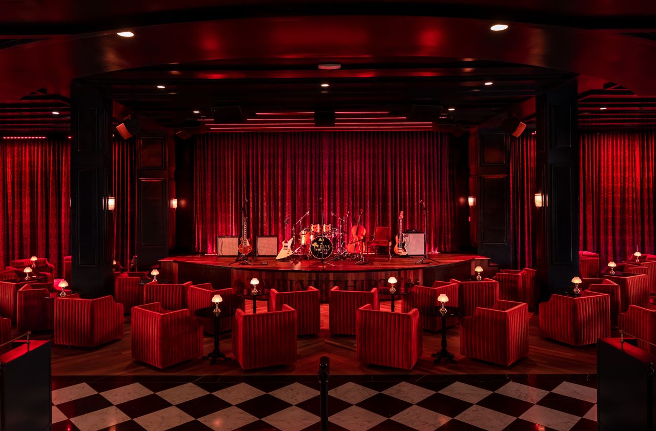 A music stage bedecked in red velvet with a lacquered black-and-white checker floor