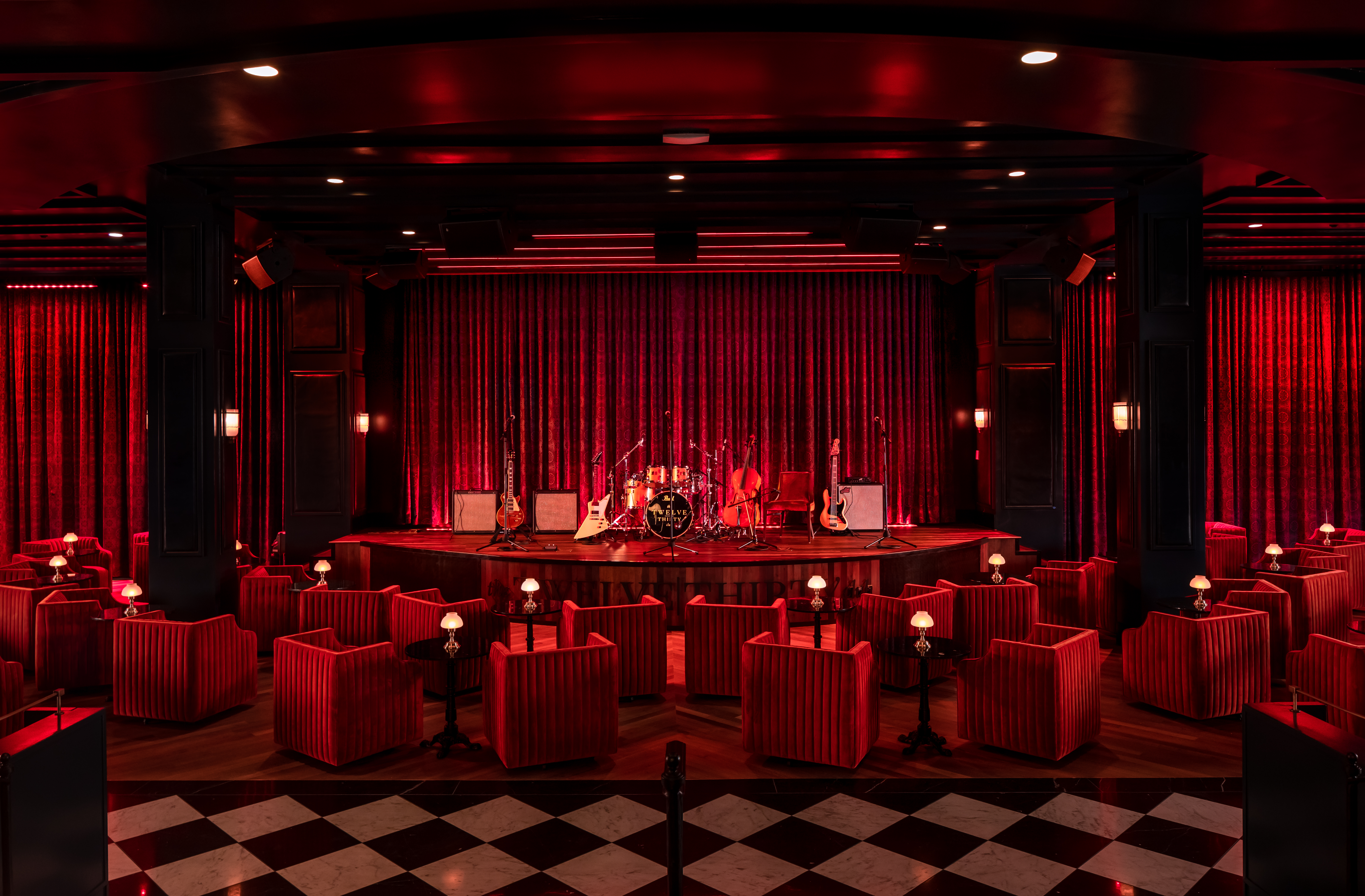 A music stage bedecked in red velvet with a lacquered black-and-white checker floor