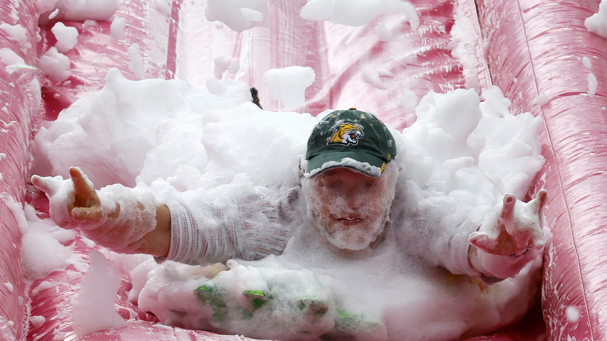 A foam-covered man slides down a pink inflatable slide during the annual event celebrating beetroot soup in Vilnius, Lithuania