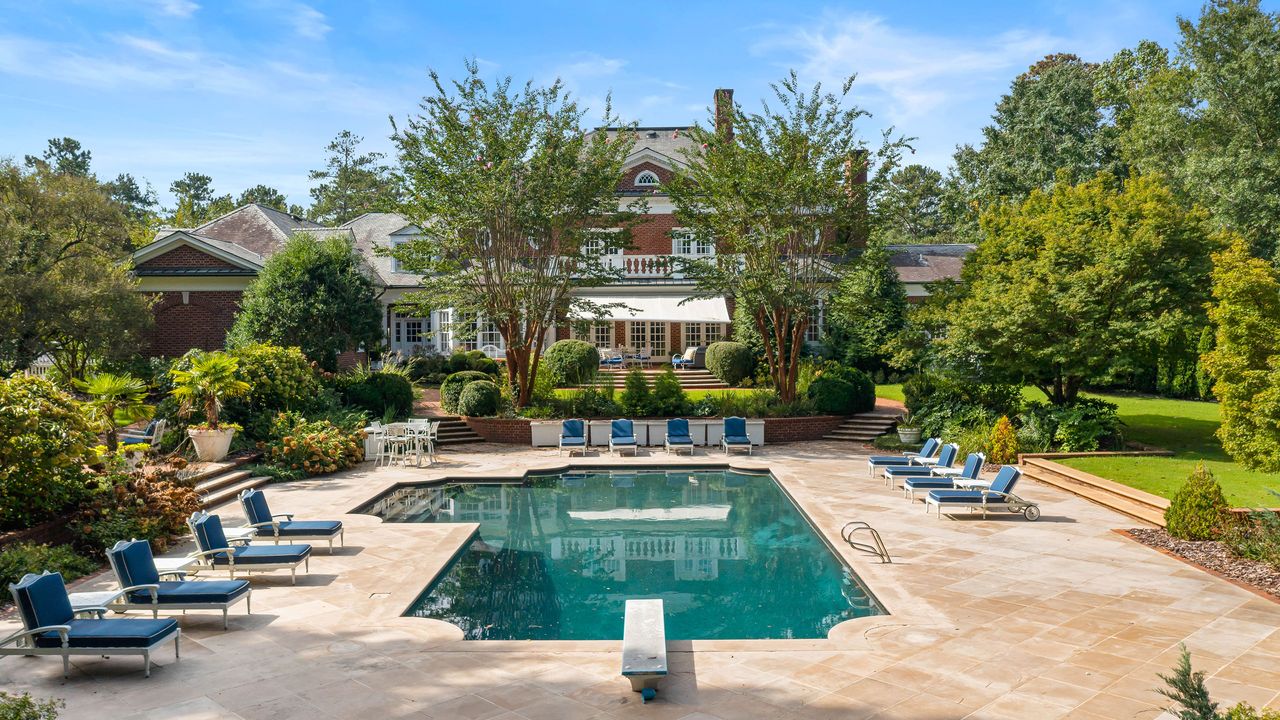 Exterior of large red brick home with pool and outdoor seating