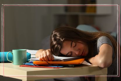 A teenage girl asleep with her head on a pile of notebooks