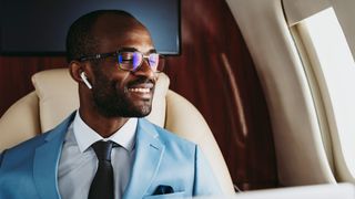 A man looks out the window of a plan while wearing AirPods