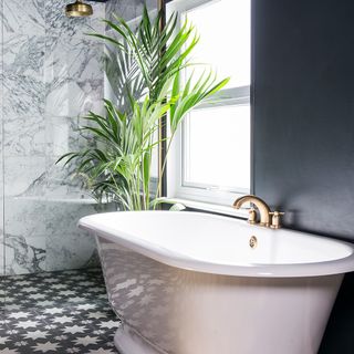 black bathroom makeover with patterned floor tiles plants and roll top bath