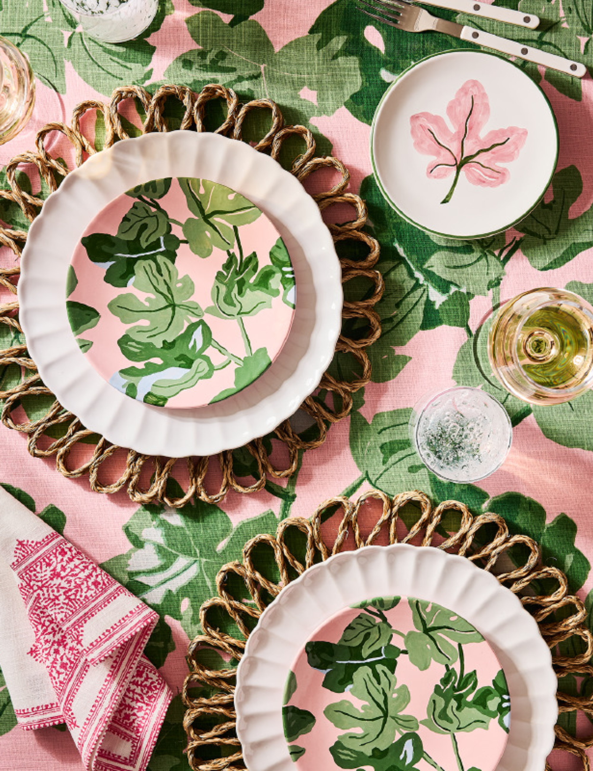 Pink-and-green patterned tablescape featuring woven scalloped accents and white Sabre cutlery