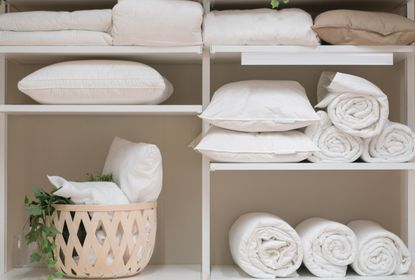 Folded white bed linen inside a closet