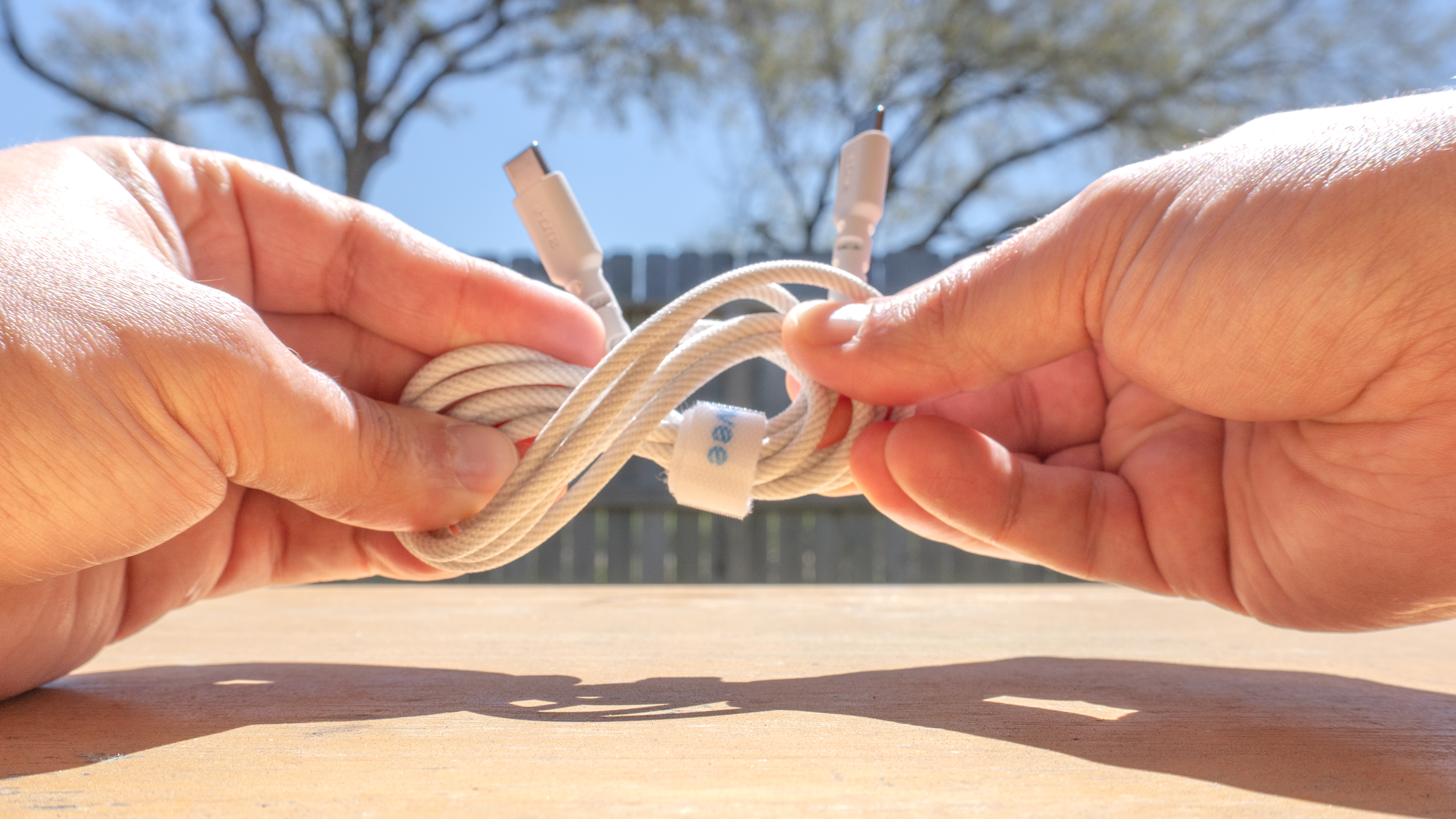 A person twisting a braided USB-C cable to make it more flexible after submerging it in water