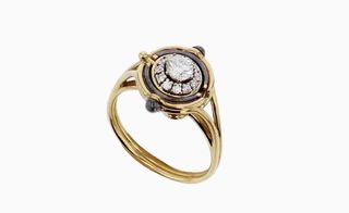 , concentric circles of yellow and blackened gold surround diamonds and rubies set in the shape of a petalled daisy