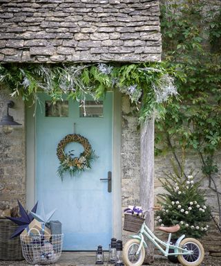 blue front door on cottage with Christmas wreath and garland