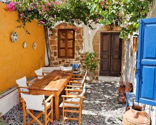 greek inspired courtyard with pergola, climbing plants, and dining set