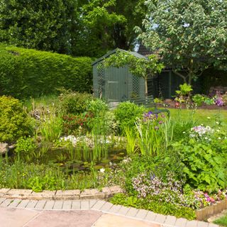 Garden with patio, pond, lawn and hedging