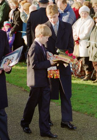 Prince William and Prince Harry hold gifts given to them by members of the public at Sandringham Church on Christmas Day