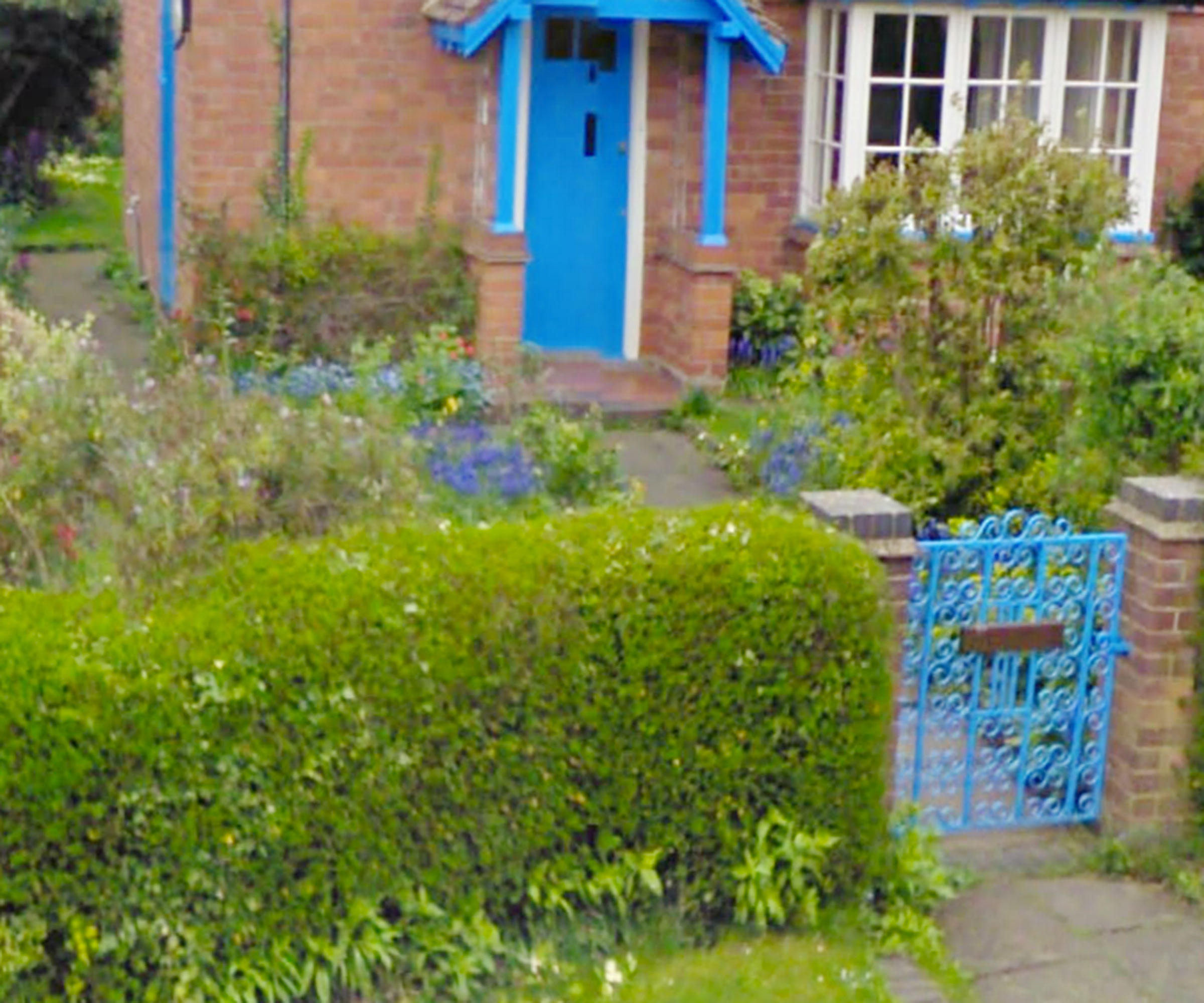 pretty cottage front garden with blue wrought iron gate