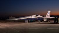 an elongated jet emblazoned with nasa logos sits on a tarmac at sunrise with the silhouettes of mountains visible in the distance