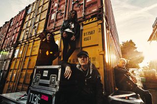 Metallica posing by some shipping containers