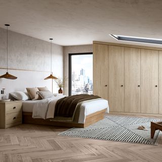 Scandi-style bedroom with chevron wood flooring, concrete walls and light wood fitted wardrobes, with a large double bed that has two hanging pendant lights either side