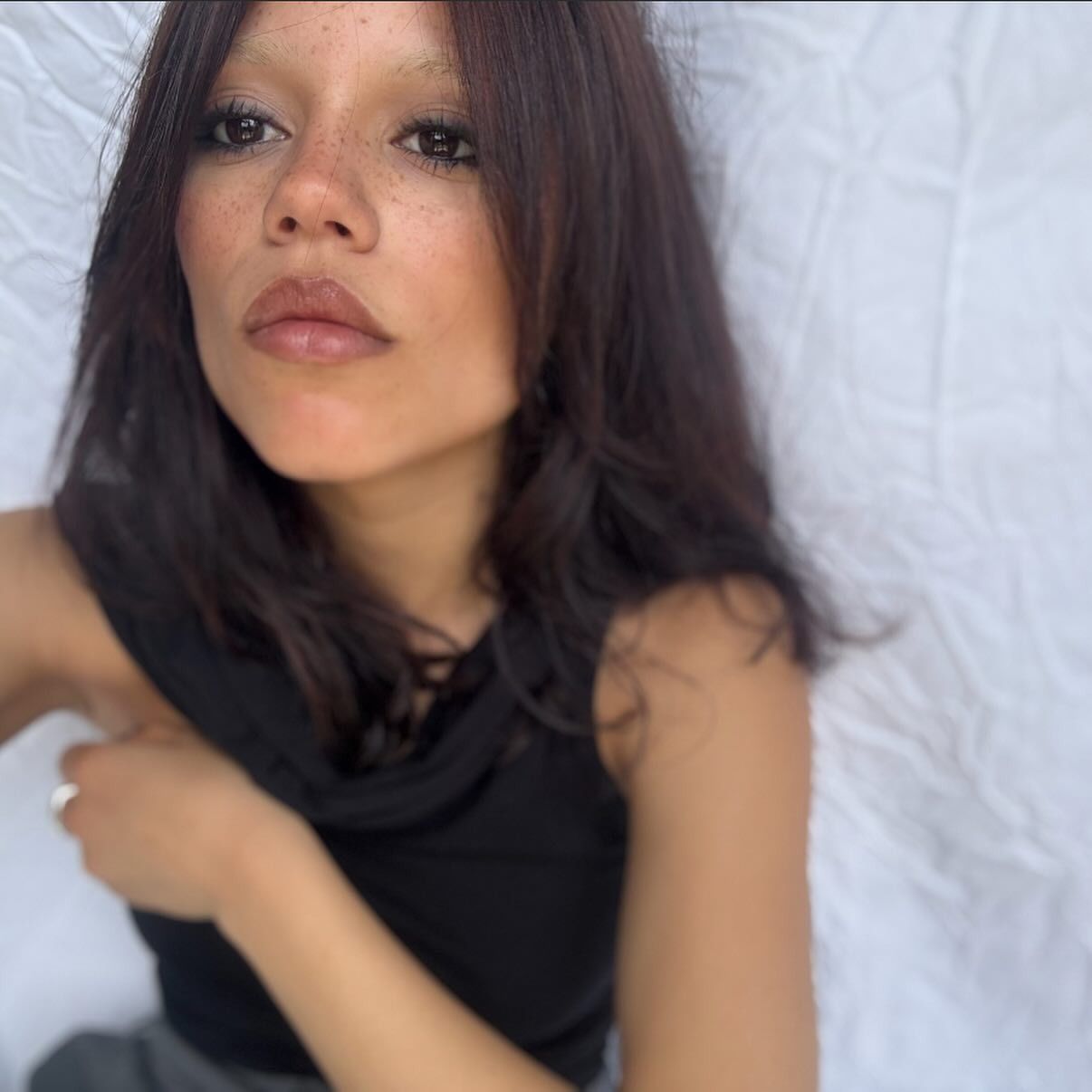 Jenn Ortega taking a selfie with a deep brunette-plum hair colour