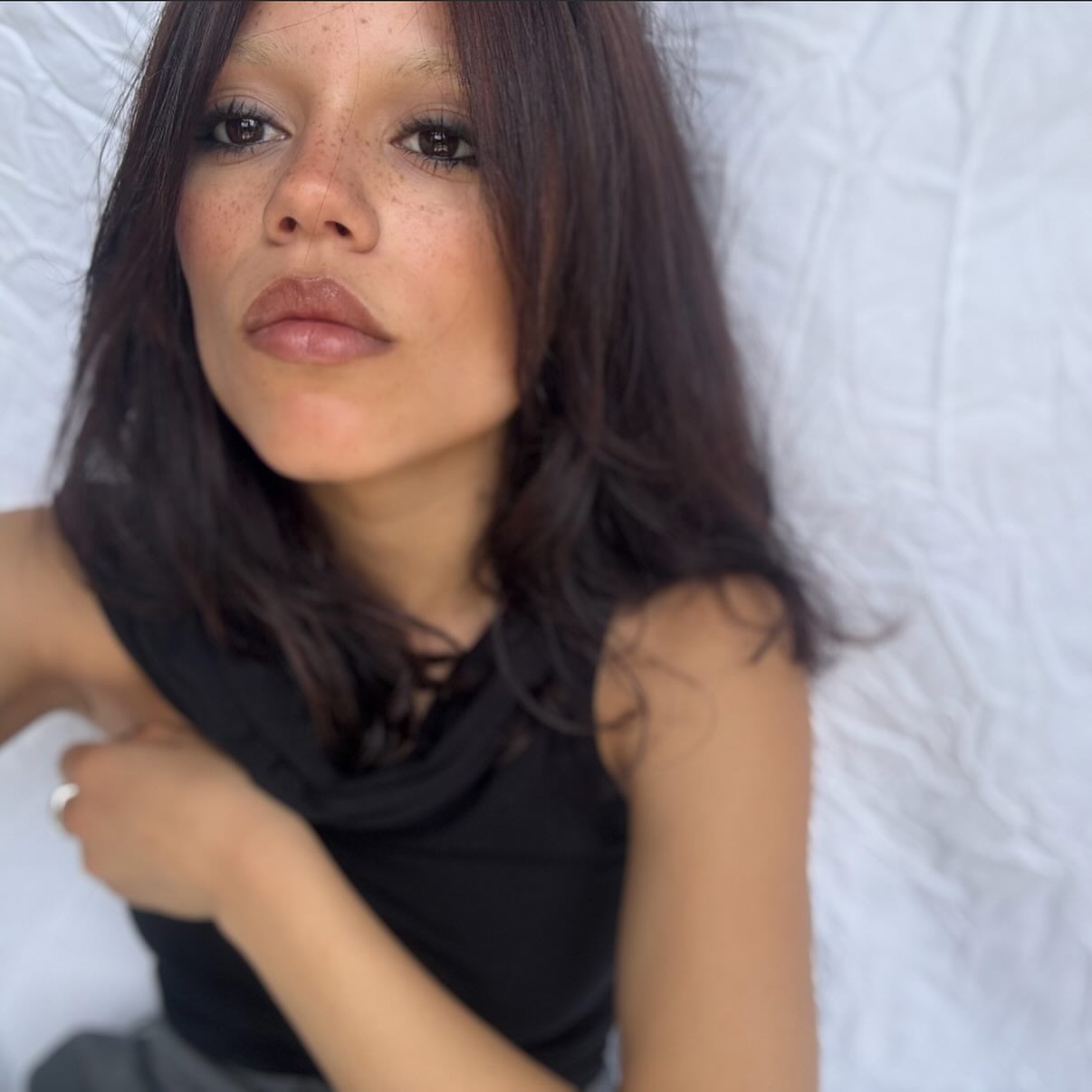Jenn Ortega taking a selfie with a deep brunette-plum hair colour