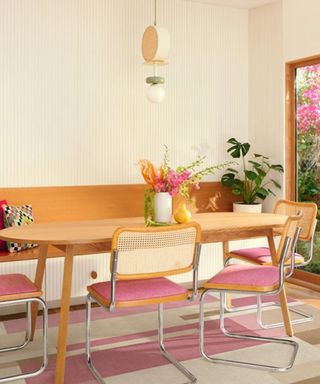 A dining table with pink seats and a pink rug