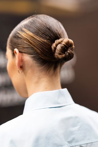 A woman pictured with a sleek, knotted bun