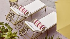 sun loungers from QVC studio 70 collection by a pool with green side table with green parasols, and green plants