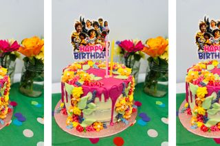 Cake covered in bright pink candy melts, fondant leaves and buttercream flowers on a party table cloth