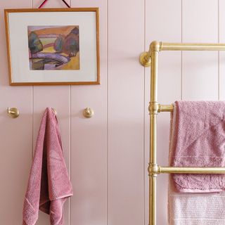 pale pink wall panelling with artwork and gold towel storage