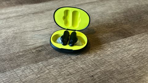 Logitech G Fits earbuds in a black and yellow case on a wooden table