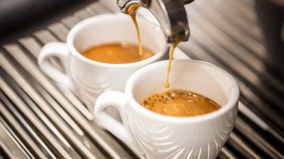 Two espresso cups being filled with shots of espresso