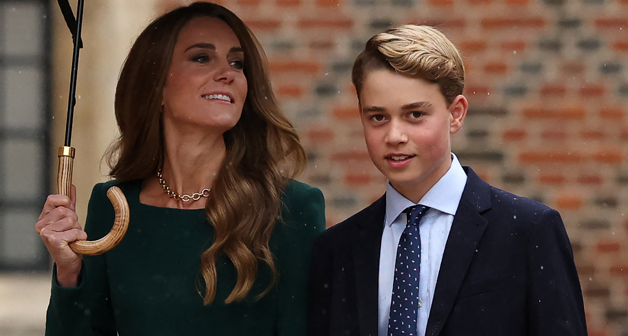 Princess Kate holding an umbrella walking next to Prince George