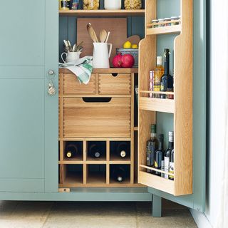 close up image of a pastel green larder in a kitchen filled with kitchen items
