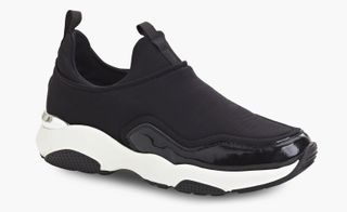 A black slip on sneaker with a white sole.